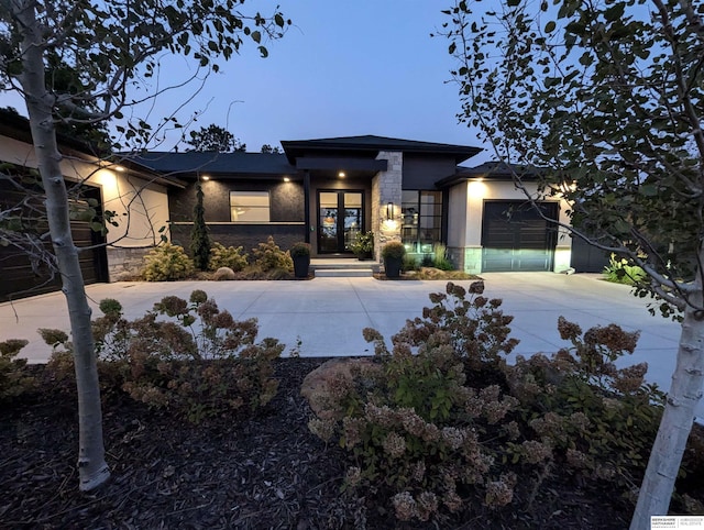 view of front of property featuring stone siding, stucco siding, an attached garage, and concrete driveway