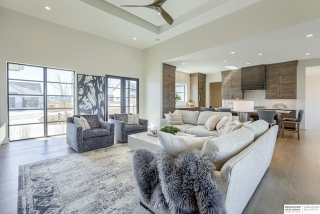 living room featuring a ceiling fan, a high ceiling, recessed lighting, and wood finished floors