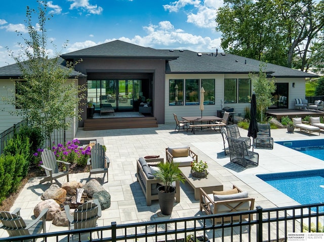 back of property featuring a fenced in pool, an outdoor hangout area, a shingled roof, and a patio area