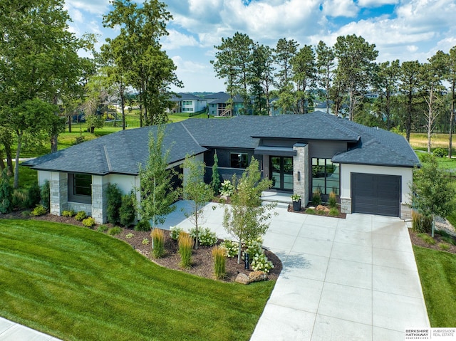 view of front of house with a front lawn, stone siding, roof with shingles, concrete driveway, and an attached garage