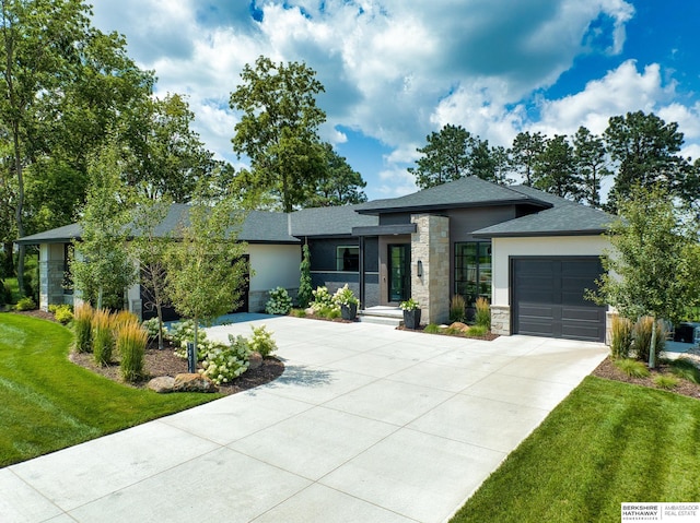 view of front of property featuring stone siding, driveway, an attached garage, and a front yard