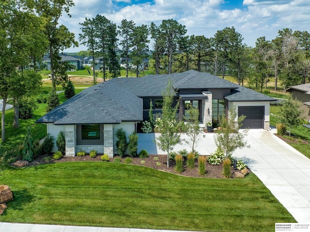 prairie-style house featuring a front yard, a garage, stone siding, and driveway