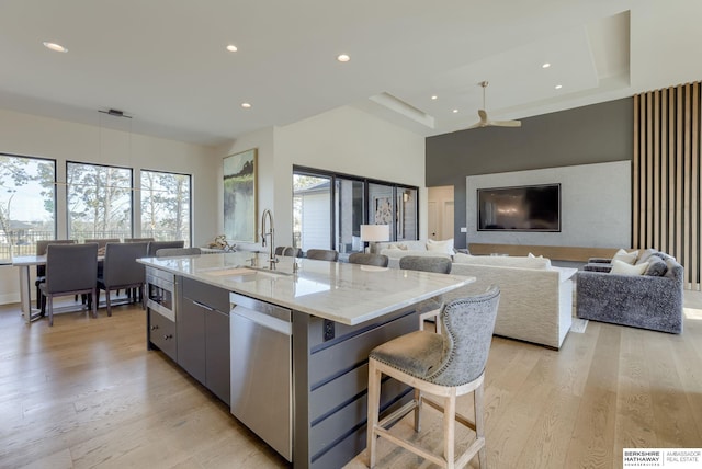 kitchen with a wealth of natural light, a kitchen island with sink, appliances with stainless steel finishes, and light wood-type flooring