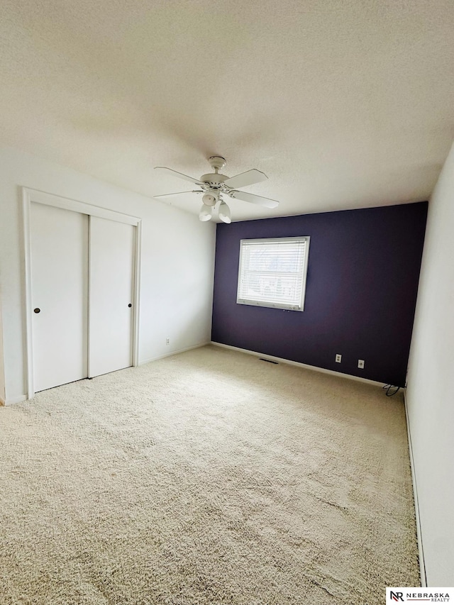 unfurnished bedroom with a closet, visible vents, carpet floors, and a textured ceiling