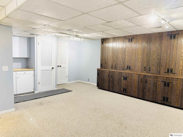 finished below grade area with wooden walls, baseboards, and a drop ceiling