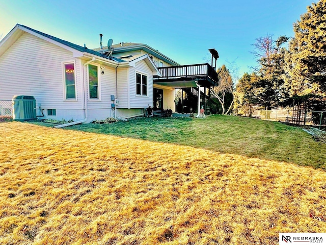 rear view of property featuring a deck, a yard, fence, and central AC