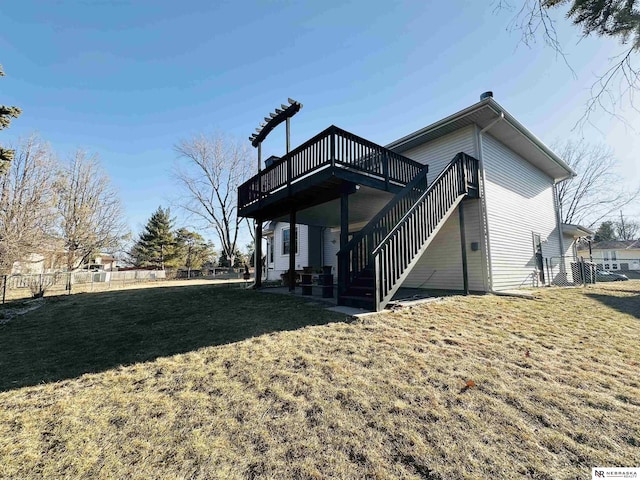 rear view of property with a yard, a wooden deck, and fence