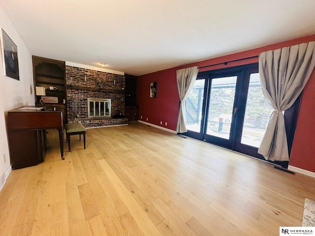 living room featuring visible vents, baseboards, wood finished floors, and a fireplace