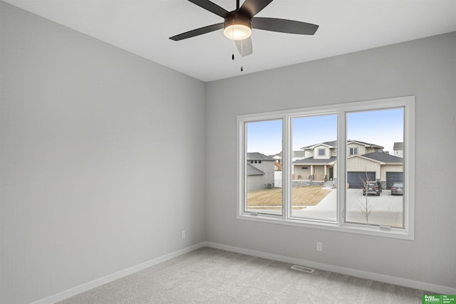 spare room featuring visible vents, light carpet, baseboards, and a ceiling fan