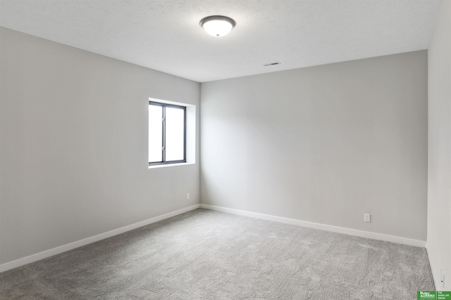 spare room featuring baseboards, carpet floors, a textured ceiling, and visible vents