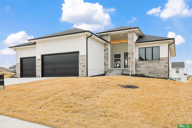 prairie-style house featuring a front yard, roof with shingles, an attached garage, stucco siding, and stone siding