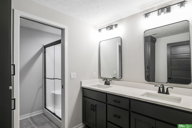 full bath featuring a stall shower, a textured ceiling, and a sink