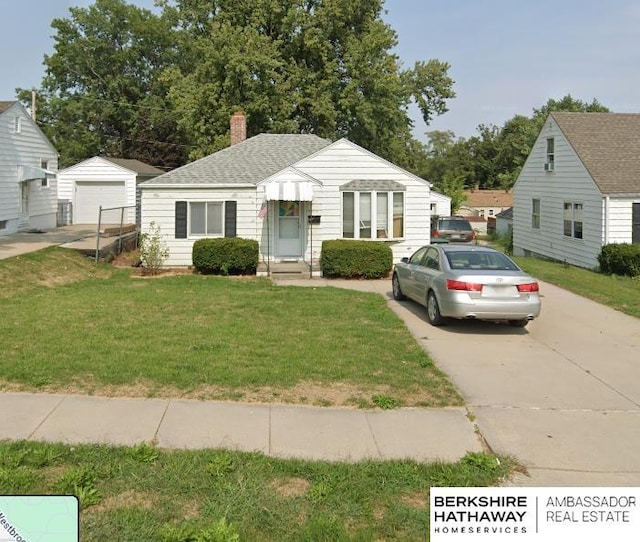 bungalow featuring a front yard, driveway, a chimney, an outdoor structure, and a garage