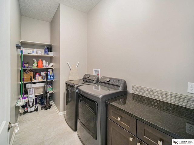 laundry area featuring independent washer and dryer, a textured ceiling, cabinet space, light tile patterned floors, and baseboards