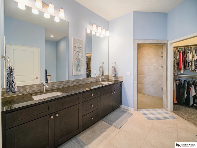 bathroom featuring double vanity, tiled shower, tile patterned floors, and a sink