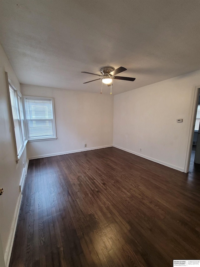 spare room with dark wood finished floors, a ceiling fan, baseboards, and a textured ceiling