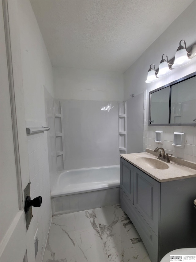 full bathroom with vanity, washtub / shower combination, marble finish floor, and a textured ceiling