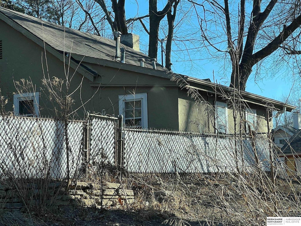 view of property exterior with fence, a chimney, and stucco siding