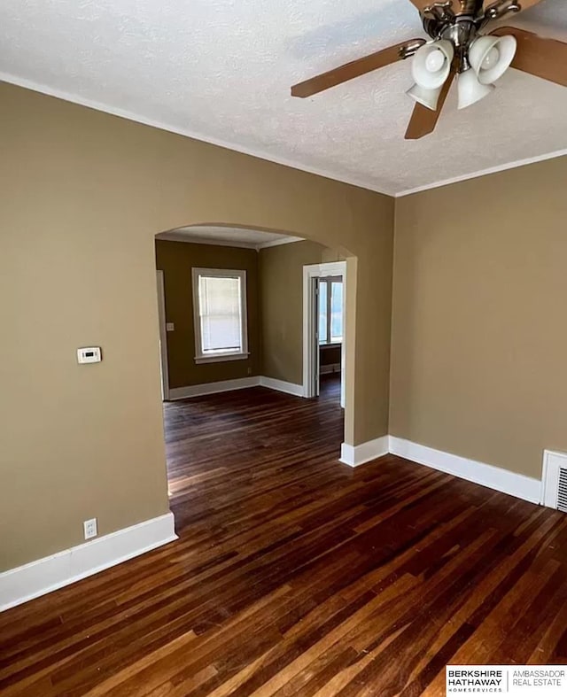 unfurnished room with arched walkways, a textured ceiling, baseboards, and wood finished floors