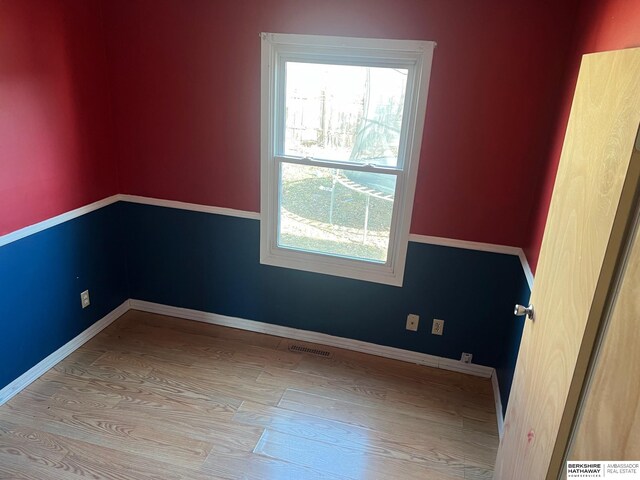 empty room with visible vents, baseboards, and wood finished floors