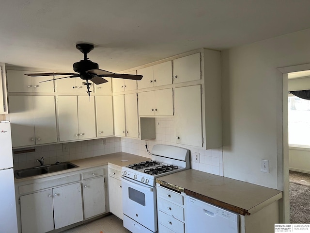 kitchen with white appliances, a ceiling fan, a sink, white cabinetry, and backsplash