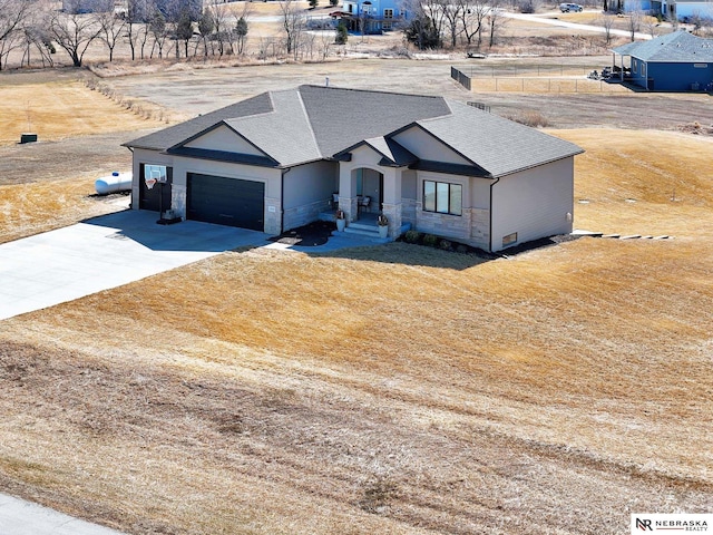 view of front of home with a shingled roof, concrete driveway, stucco siding, a garage, and stone siding