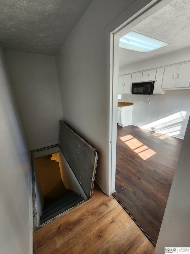 stairway with wood finished floors and a textured ceiling