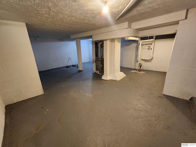 unfinished below grade area featuring heating unit and a textured ceiling