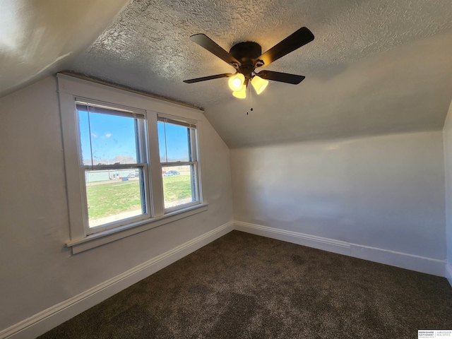 bonus room with vaulted ceiling, baseboards, dark carpet, and a textured ceiling