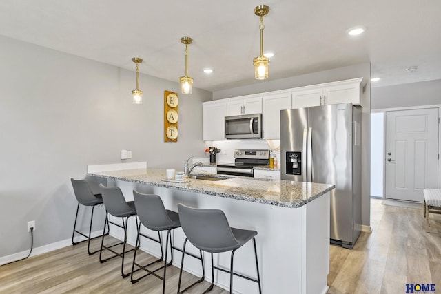 kitchen with a breakfast bar, a peninsula, a sink, and stainless steel appliances