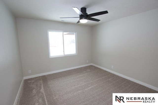 carpeted spare room featuring baseboards and ceiling fan