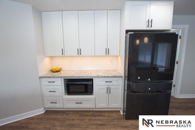 kitchen with light stone countertops, black appliances, dark wood-style floors, and white cabinets