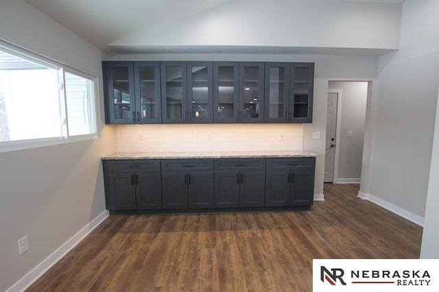 bar featuring dark wood-style floors, backsplash, baseboards, and vaulted ceiling