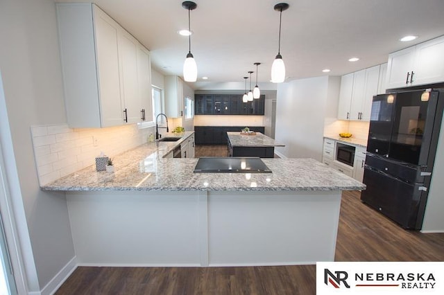 kitchen with a center island, light stone countertops, a peninsula, black appliances, and a sink