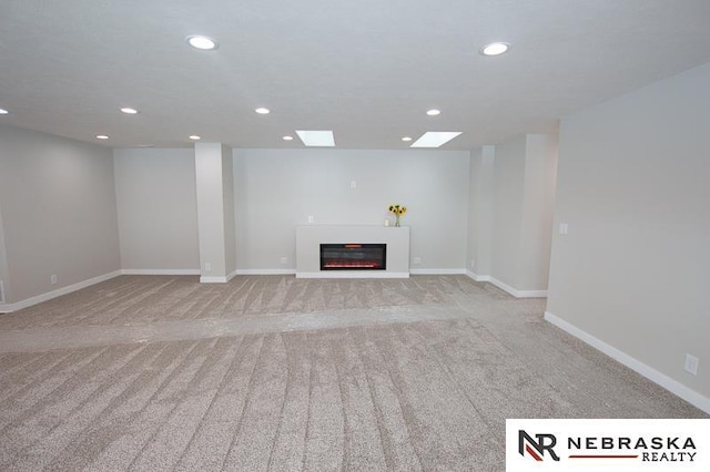 unfurnished living room with a glass covered fireplace, carpet flooring, recessed lighting, and baseboards