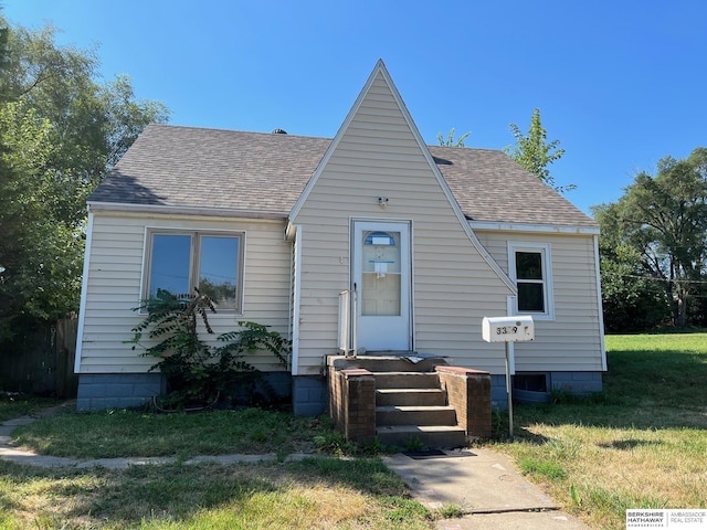 view of front of property featuring a front yard and a shingled roof