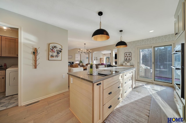 kitchen featuring visible vents, baseboards, a chandelier, light wood-type flooring, and washer / dryer