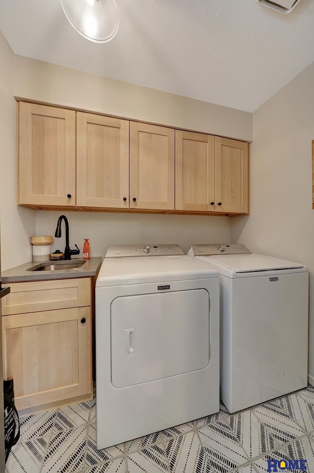 laundry area featuring washer and dryer, light tile patterned flooring, cabinet space, and a sink