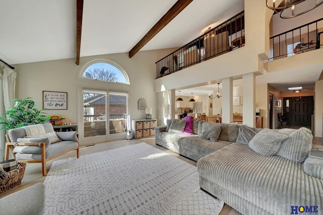 living room featuring beamed ceiling, a high ceiling, and an inviting chandelier