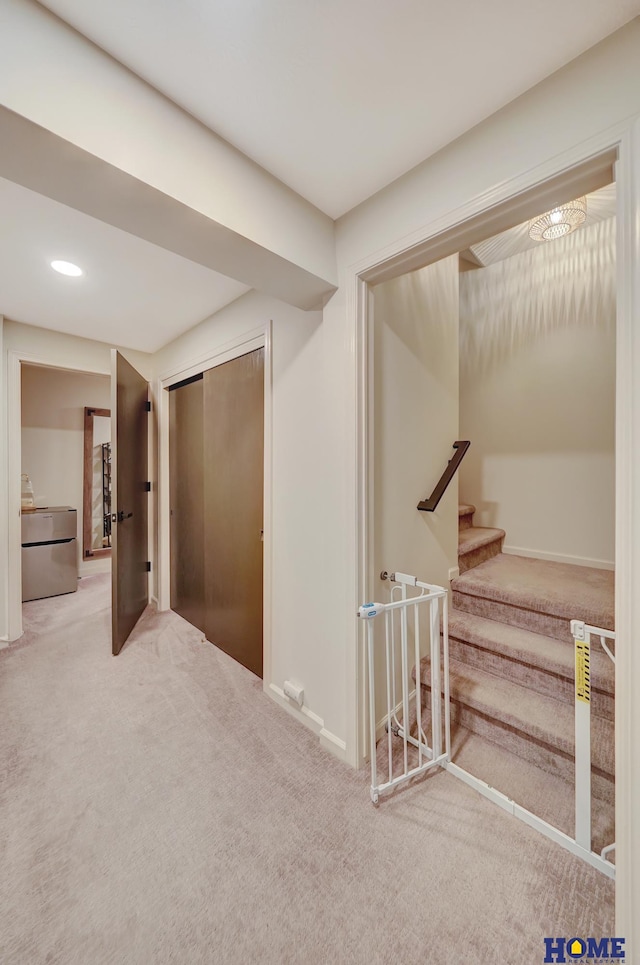 hallway featuring carpet flooring, baseboards, and stairs