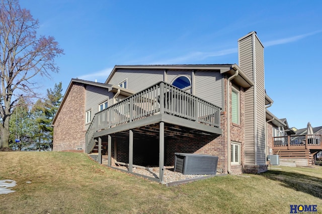 rear view of house featuring a wooden deck, a lawn, central AC unit, and a chimney