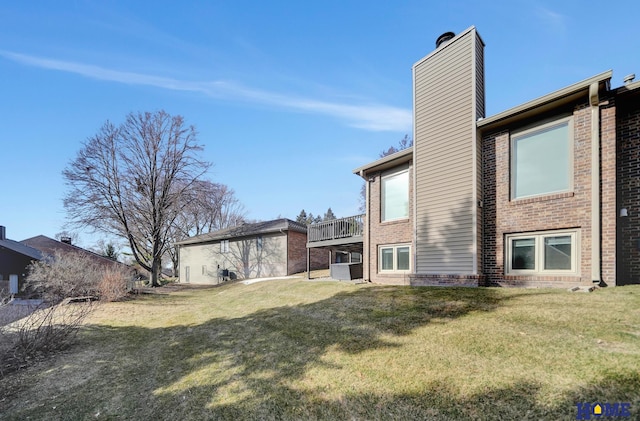 back of house featuring a yard, brick siding, and a chimney