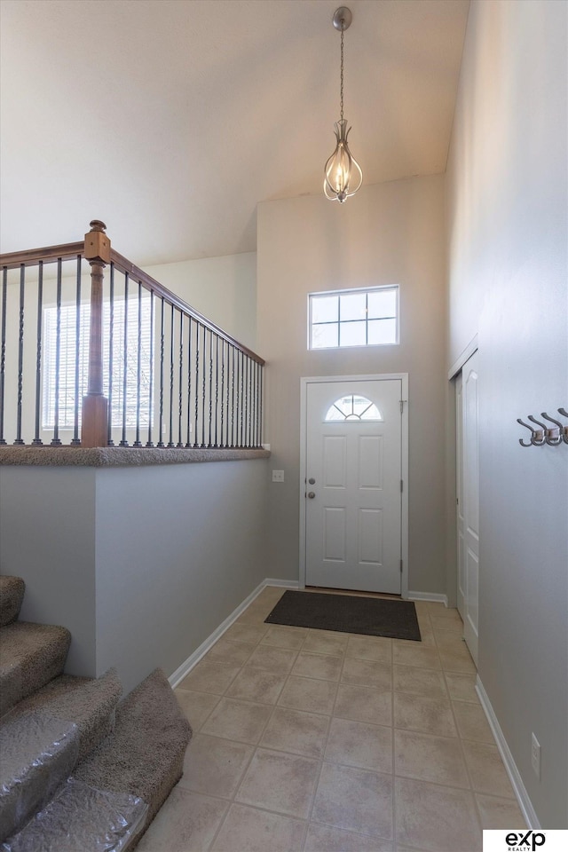 entrance foyer with stairs, a high ceiling, light tile patterned floors, and baseboards