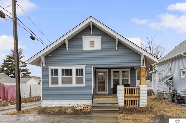 bungalow-style home featuring covered porch and fence