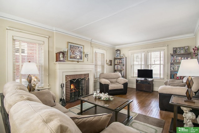 living area with a brick fireplace, baseboards, wood-type flooring, and ornamental molding