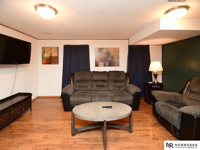 living area featuring light wood-style floors, visible vents, and baseboards