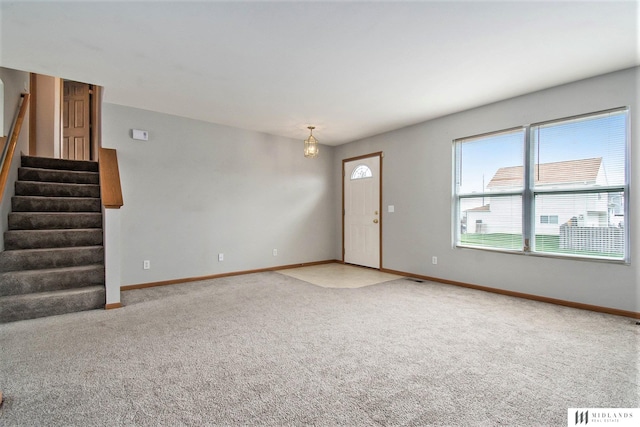 unfurnished living room with stairs, baseboards, and carpet floors