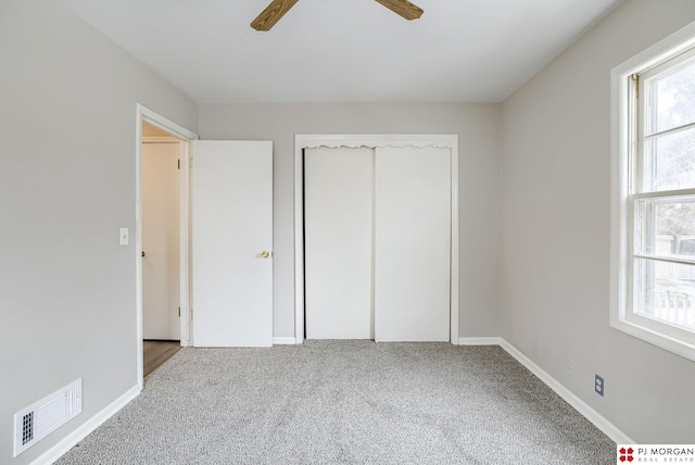 unfurnished bedroom with visible vents, a closet, carpet flooring, baseboards, and ceiling fan