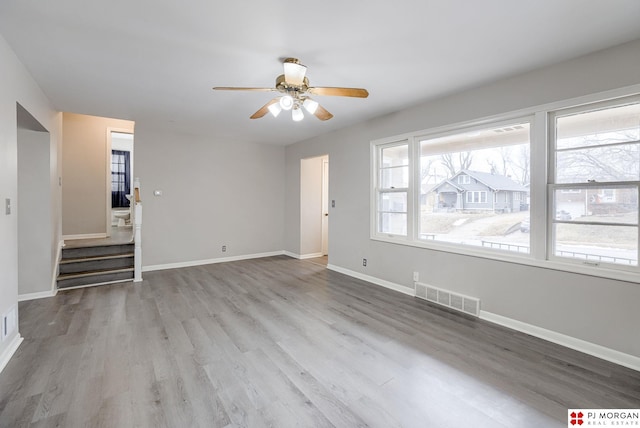 unfurnished living room with ceiling fan, visible vents, baseboards, and wood finished floors