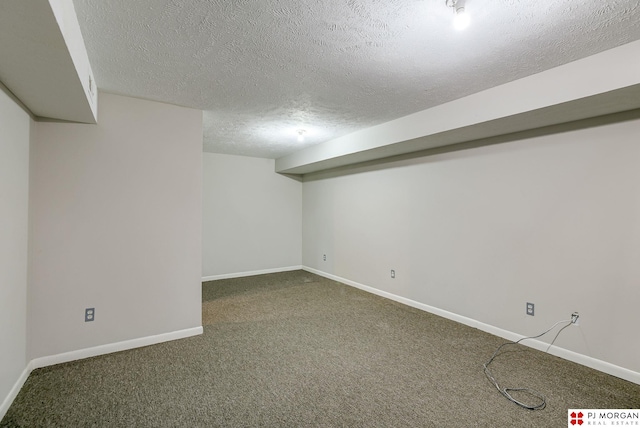 finished below grade area featuring baseboards, carpet, and a textured ceiling